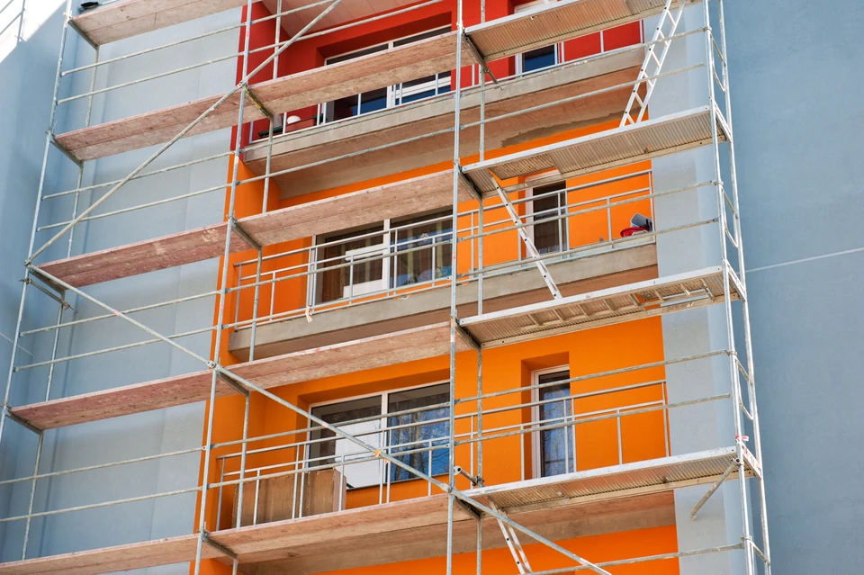 Chantier de rénovation extérieure d'immeuble résidentiel avec ouvriers sur échafaudage tubulaire