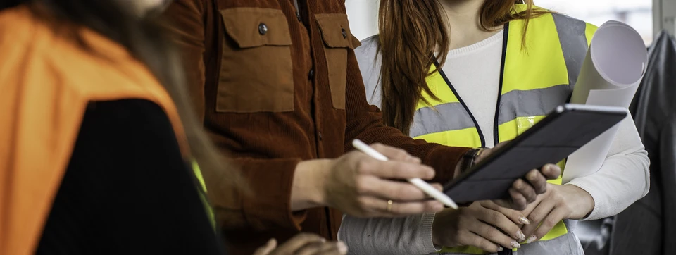 Ouvrier en tenue de travail installant des panneaux de placo sur mur intérieur, chantier de construction avec mur en briques apparentes