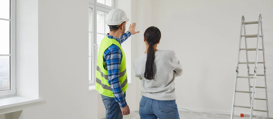Homme en tenue de chantier avec casque de sécurité blanc consultant des plans architecturaux sur site de construction extérieur